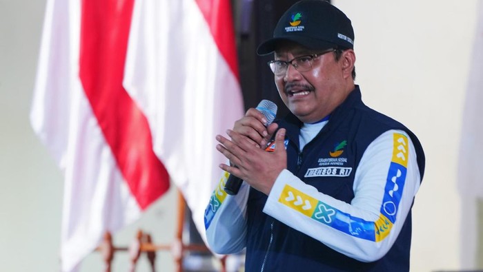 Seorang pejabat berbicara dengan penuh semangat tentang kebijakan batas waktu penerima bansos, di tengah latar belakang bendera nasional, menegaskan dampak signifikan dari perubahan ini yang bisa mengejutkan banyak orang.