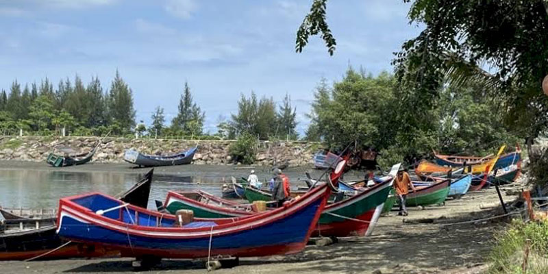 Nelayan Aceh beristirahat di tepi pantai, mengenang tragedi tsunami yang mengguncang kehidupan mereka, sambil menghormati hari peringatan dengan tidak melaut.
