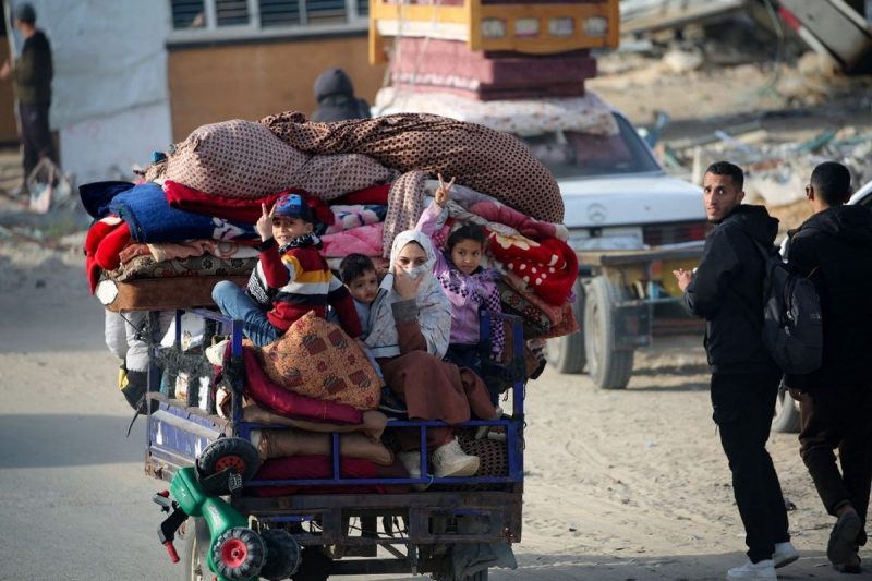 Anak-anak dan seorang wanita terlihat duduk di atas tumpukan barang di sebuah kendaraan yang melintas di jalanan Gaza. Gambar ini mencerminkan situasi sulit yang dihadapi warga sipil akibat ketegangan yang terus meningkat, meskipun gencatan senjata telah diterapkan.