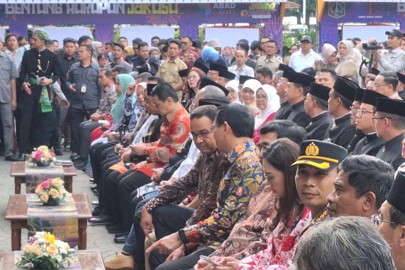 Ahok dan Anies duduk berdampingan di Balai Kota, menunjukkan momen rekonsiliasi yang tak terduga, dikelilingi oleh para pejabat dan masyarakat yang antusias menyaksikan pertemuan bersejarah ini.