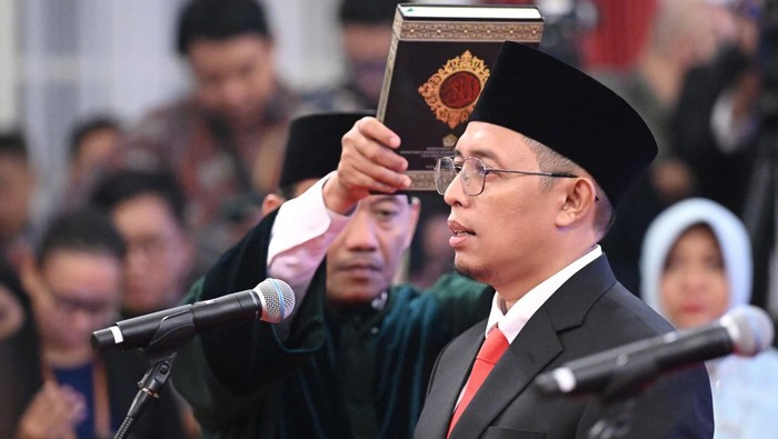 Dalam gambar ini, terlihat momen penting saat seorang pejabat dilantik, dengan Presiden yang menyaksikan dan menyerahkan kitab sebagai simbol tanggung jawab.